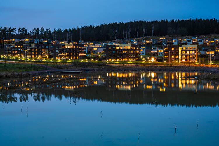 Nya stödverktyg för energiplanering. Vacker kvällsbild från en sjö in mot land där lamporna lyser i flerfamiljshusen.